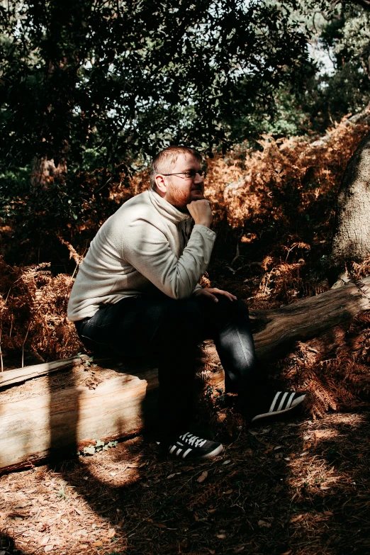 a man sitting on a log in the woods, profile image, conor walton, casually dressed, lee griggs