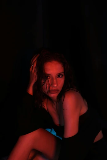 a woman sitting on a bed in the dark, an album cover, trending on pexels, realism, red neon, girl with brown hair, dramatic serious pose, gif