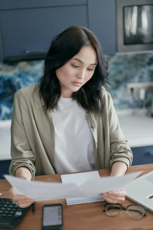 a woman sitting at a table with papers and a calculator, pexels contest winner, renaissance, black haired girl wearing hoodie, in a kitchen, wearing business casual dress, asian woman