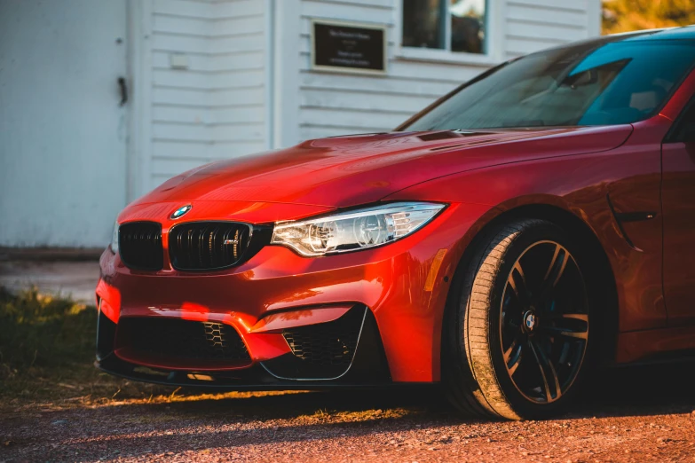 a red car parked in front of a white house, pexels contest winner, bmw, golden hour closeup photo, [ 4 k photorealism ], multi chromatic