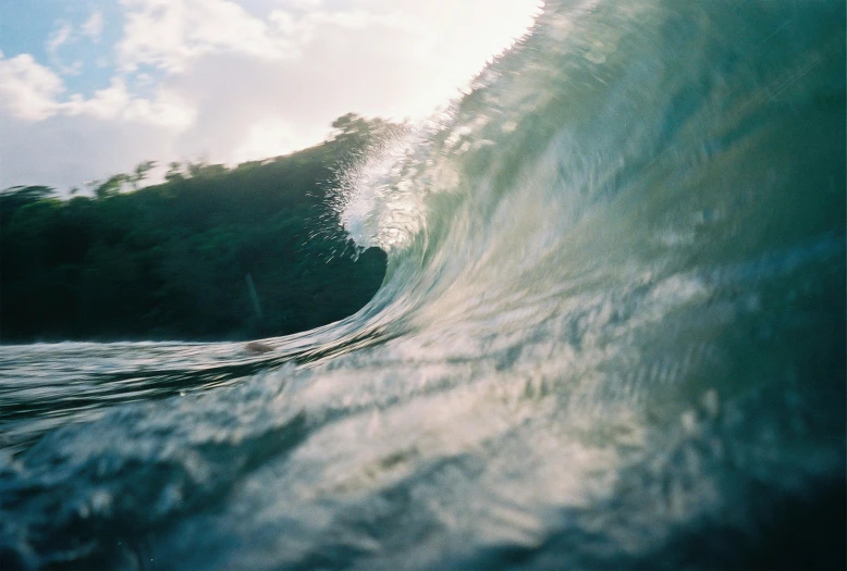 a man riding a wave on top of a surfboard, unsplash contest winner, photorealism, vsco film grain, inside the curl of a wave, golden hour closeup photo, blue and green water