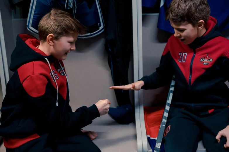 two young boys sitting next to each other in a locker, pexels, still from avengers endgame, wearing track and field suit, reaching out to each other, red and blue garments