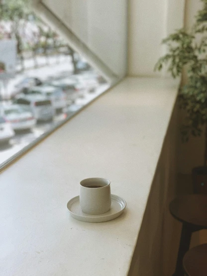 a cup of coffee sitting on a table in front of a window, by Harvey Quaytman, kyoto inspired, low quality photo, multiple stories, detailed product image