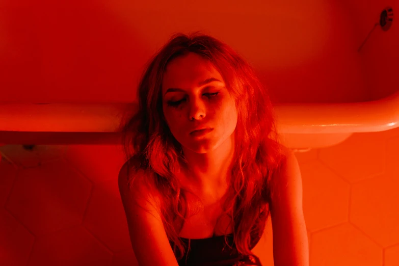 a woman sitting on the floor in front of a bathtub, inspired by Nan Goldin, pexels contest winner, antipodeans, orange and red lighting, portrait of annasophia robb, red cloud light, kiera knightly in repose