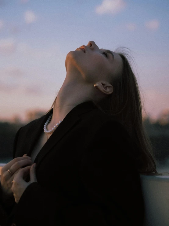 a woman is looking up at the sky, inspired by Elsa Bleda, trending on pexels, aestheticism, resting on chest, woman in black business suit, wearing choker, with pale skin