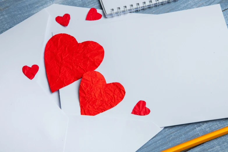 a couple of red hearts sitting on top of a piece of paper, pexels contest winner, mail art, whiteboards, thumbnail, educational supplies, 9 9 designs