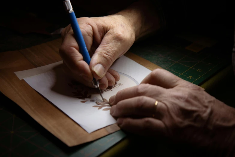 a close up of a person writing on a piece of paper, photorealism, crafts, light tracing, brown, traditional art
