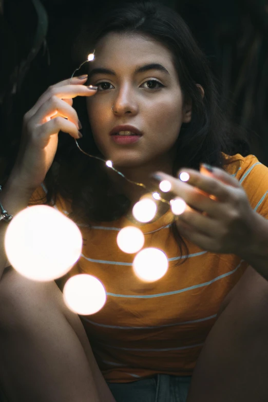 a woman sitting on the ground holding a string of lights, pexels contest winner, light bulbs, close up portrait photo, lumen reflections, teenage girl