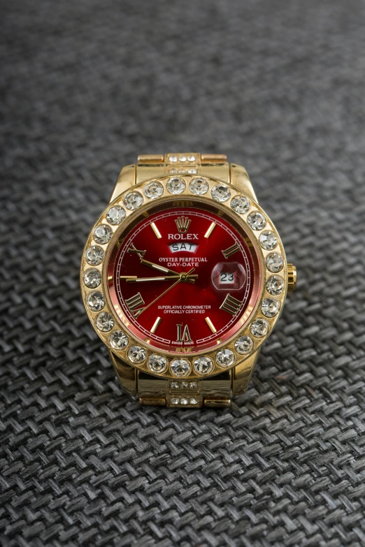 a red watch sitting on top of a table, a portrait, with sparkling gems on top, thumbnail, golden, premium