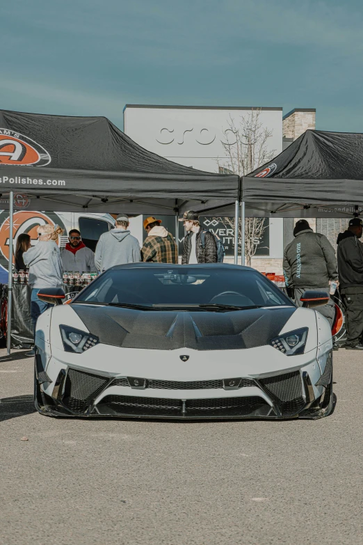 a white and black sports car parked in a parking lot, in front of a large crowd, bold lamborghini style, hextech, colorado