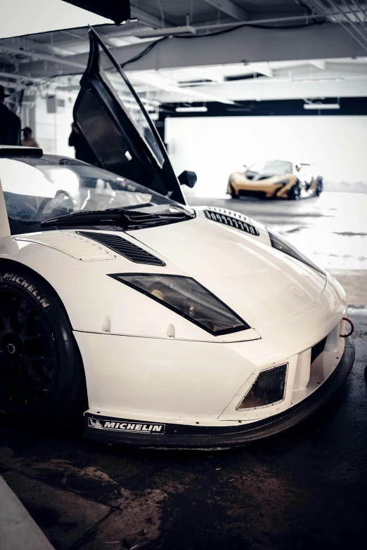 a white sports car parked in a garage, a photo, unsplash, veneno, close up angle, at racer track, uploaded