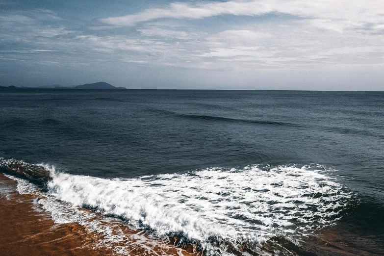 a man riding a surfboard on top of a sandy beach, pexels contest winner, realism, dark blue water, ocean shoreline on the horizon, charybdis, quixel megascan