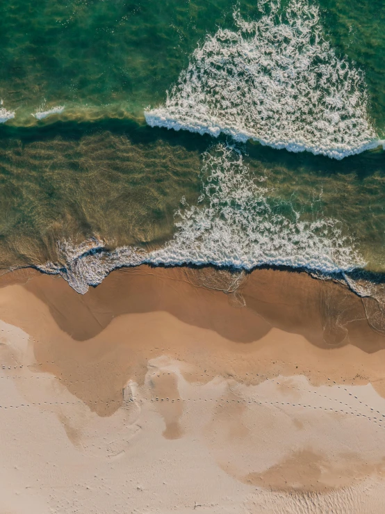 a large body of water next to a sandy beach, by Lee Loughridge, unsplash contest winner, happening, bird\'s eye view, high detail 4 k, manly, soaring waves