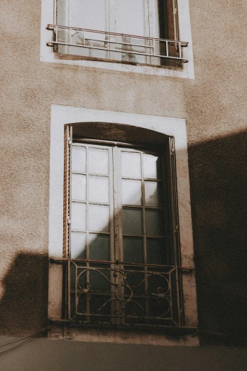 a black and white photo of a building with a window, pexels contest winner, tonalism, sunfaded, big french door window, (golden hour), french village exterior