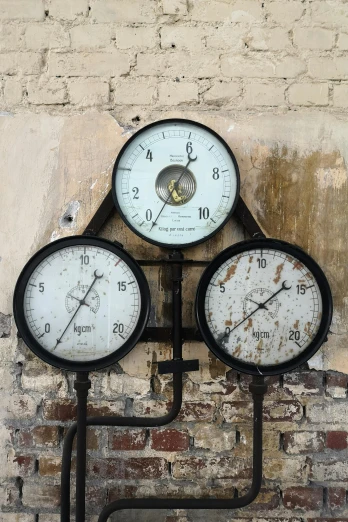 three clocks mounted to the side of a brick wall, unsplash, kinetic art, gauges, retro machinery, faded worn, hydraulics