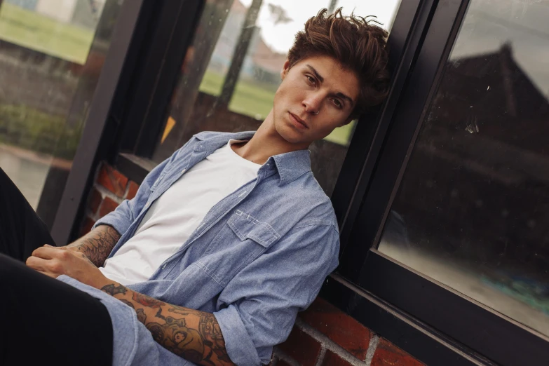 a close up of a person sitting on a window sill, a portrait, inspired by Luca Zontini, trending on pexels, wearing a shirt and a jean, androgynous male, posing for a picture, inked