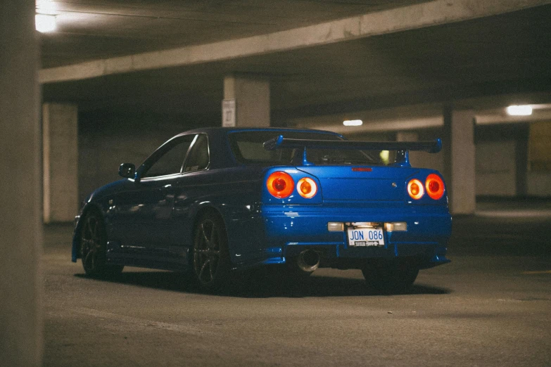 a blue car parked in a parking garage, inspired by Kanō Hōgai, pexels contest winner, in a modified nissan skyline r34, rear lighting, avatar image