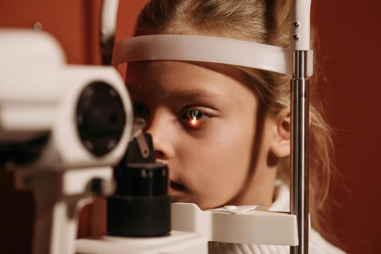 a woman looking through an eye exam machine, a picture, by Adam Marczyński, shutterstock, hyperrealism, black eyed kids, looking up at the camera, medical, orange pupils