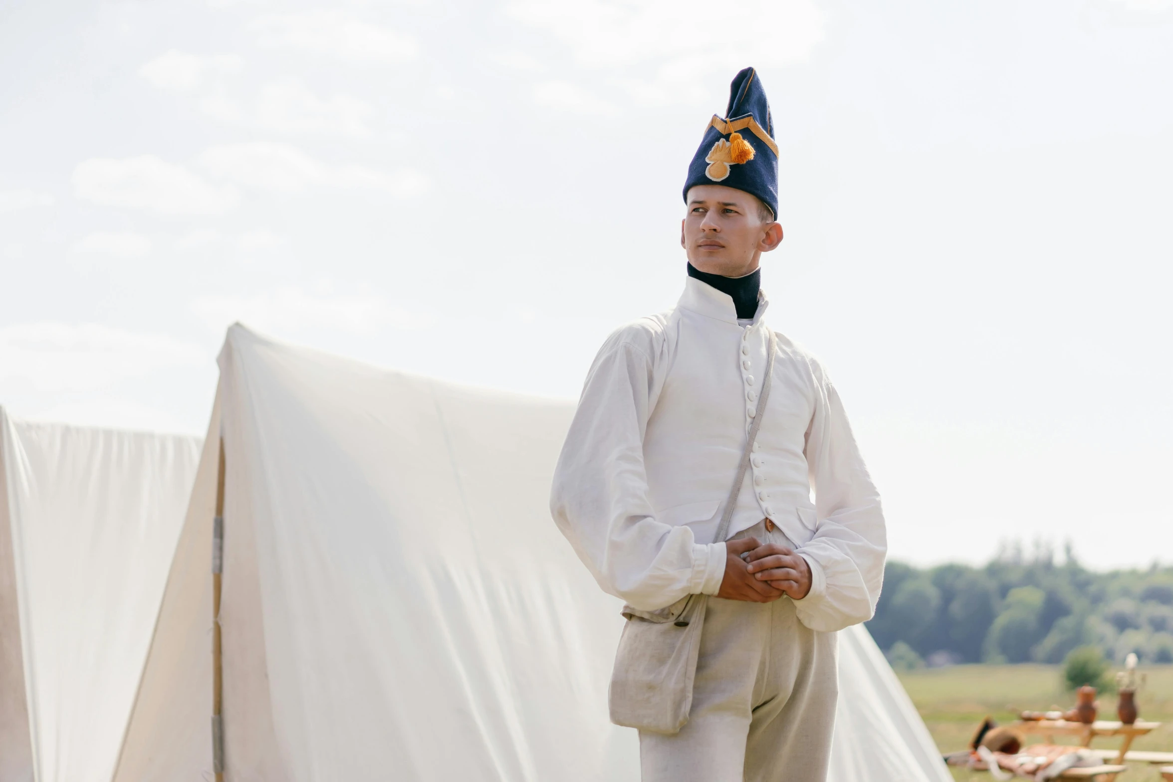 a man in uniform standing in front of a tent, inspired by Horace Vernet, unsplash, white uniform, still image from tv series, blue sky, traditional clothing