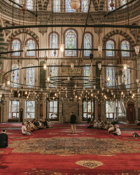 a group of people sitting on top of a red carpet, by Meredith Dillman, pexels contest winner, hurufiyya, mosque interior, large stained glass windows, gif, 2 0 2 2 photo