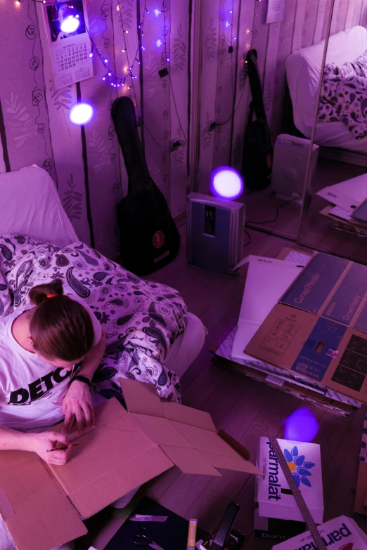 a woman laying on top of a bed covered in boxes, an album cover, by Jessie Alexandra Dick, pexels contest winner, brightly lit purple room, tactile buttons and lights, incubator medpods, tending on art station