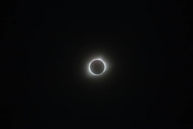 an eclipse is seen in the dark sky, by Erwin Bowien, unsplash, bauhaus, silver, from wheaton illinois, cell phone photo, 300mm lense