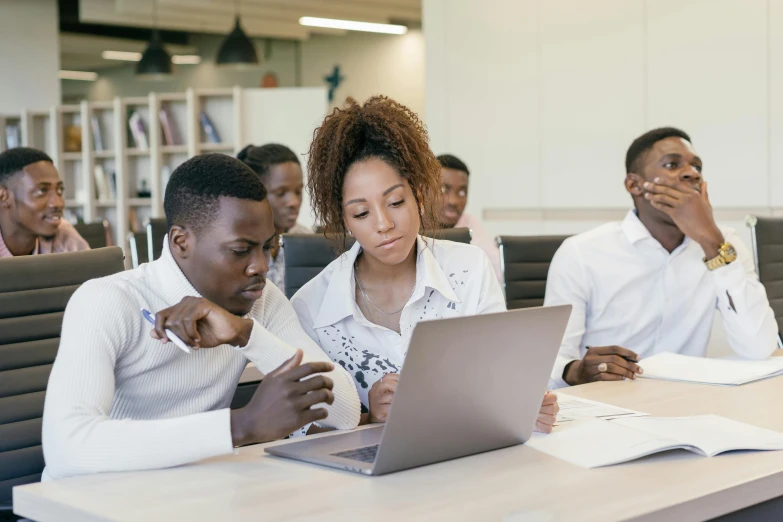 a group of people sitting around a table looking at a laptop, standing in class, african canadian, background image, visuals