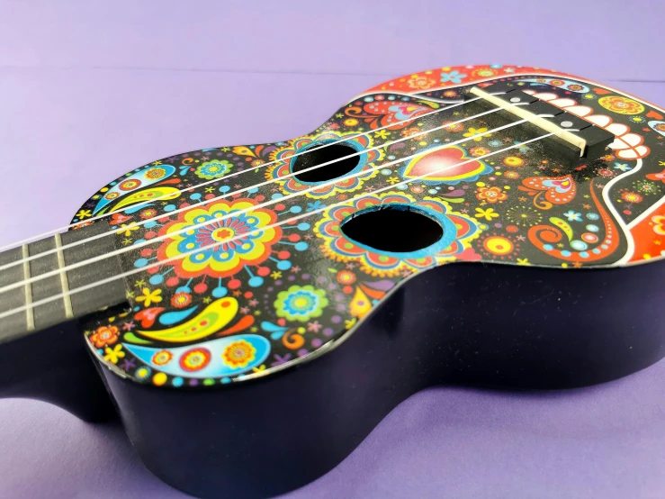 a colorful ukulele sitting on top of a purple surface, toyism, calavera, made of smooth black goo, detailed product image, paisley