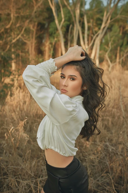 a woman posing for a picture in a field, an album cover, by Robbie Trevino, trending on pexels, portrait of modern darna, white sleeves, soft backlighting, asher duran