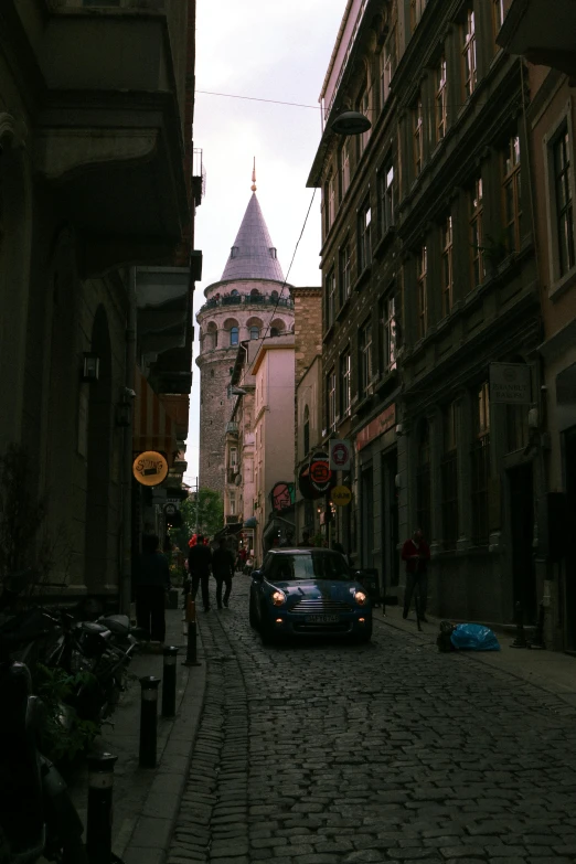 a car driving down a cobblestone street next to tall buildings, neoclassical tower with dome, turkish and russian, facing away from camera, square