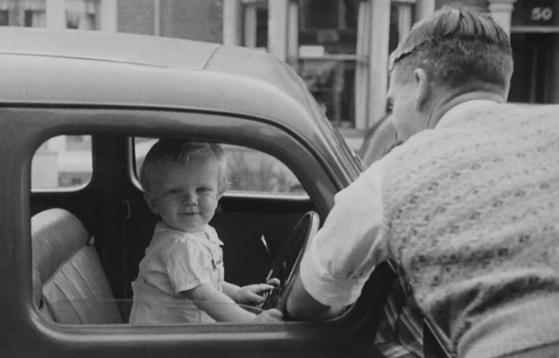 a little girl sitting in the driver's seat of a car, by Bert Hardy, digital image, father with child, 1950s press photo, abcdefghijklmnopqrstuvwxyz