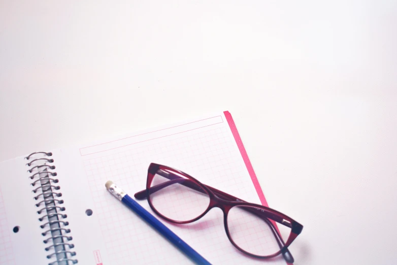 a pair of glasses sitting on top of a notebook, magenta and blue, pencil, shot on sony a 7, square glasses