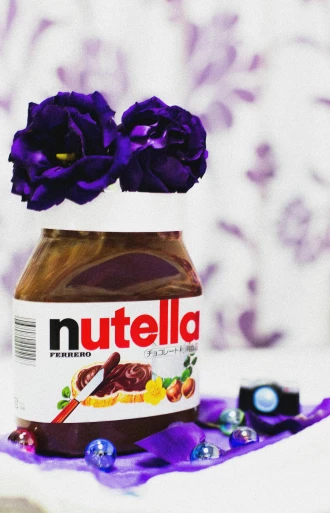 a jar of nutella sitting on top of a table, an album cover, by Julia Pishtar, pexels, purple flowers, ((purple))