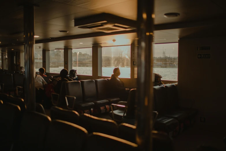 a group of people sitting on top of a train, inside large window of ship, unsplash photography, golden glow, sitting in a lounge