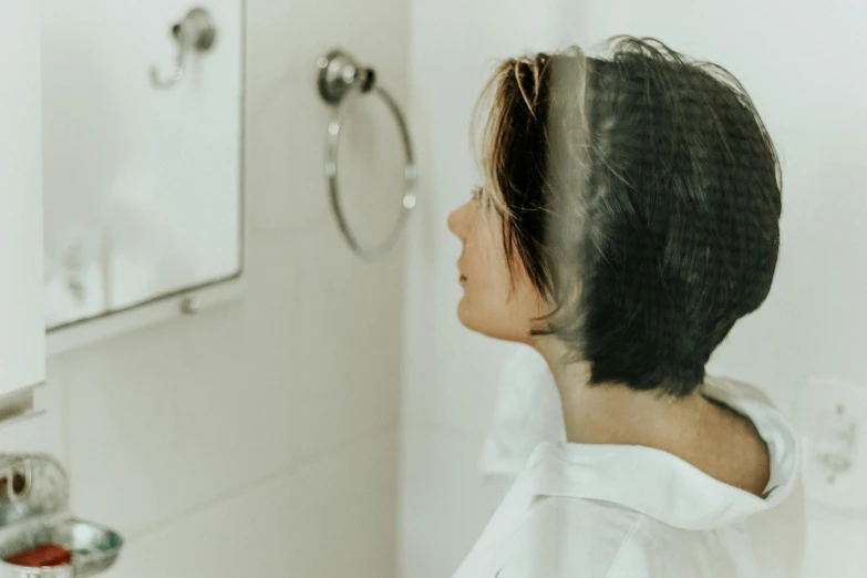a woman standing in front of a mirror in a bathroom, pexels contest winner, detailed hair foggy, profile image, background image, short hair
