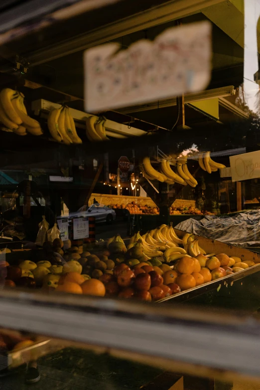 a display case filled with lots of different types of fruit, by Niko Henrichon, trending on unsplash, evening sunlight, giant bananas natural disaster, from street level, seen from below