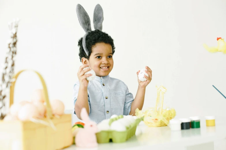 a little boy that is sitting at a table, holding easter eggs, with pointy ears, varying ethnicities, foam