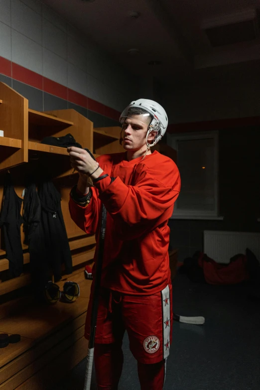 a man standing in a locker holding a baseball bat, by Andrew Domachowski, pexels contest winner, carey price goaltender, red uniform, tom bangshaw, asher duran