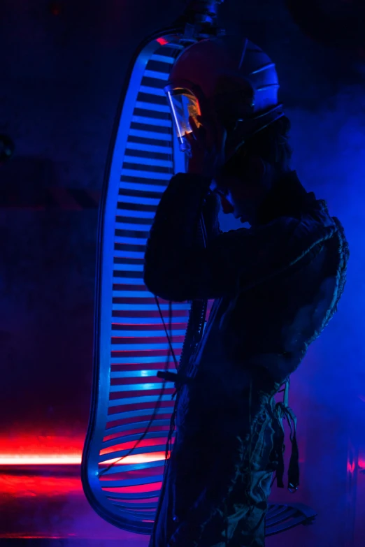 a man that is standing in front of a chair, inspired by Joseph Wright of Derby, unsplash, kinetic art, synthesizers, live performance, cold studio lighting, with an harp