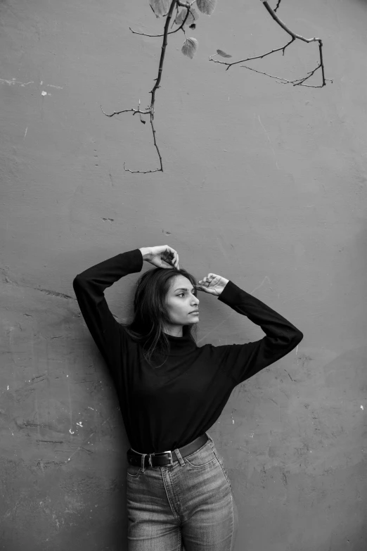 a black and white photo of a woman leaning against a wall, pexels contest winner, antipodeans, wearing a black sweater, arms extended, zaha hadi, alexey gurylev