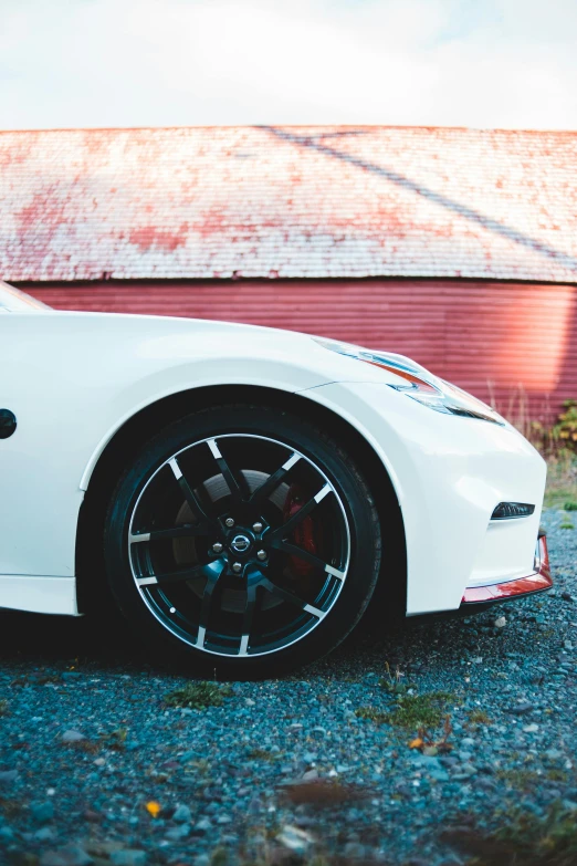 a white sports car parked in front of a barn, a photo, unsplash, red and black details, black wheel rims, profile picture, multiple stories