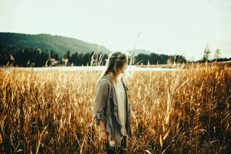 a woman standing in a field of tall grass, pexels contest winner, earthy colors, instagram post, handsome girl, looking out