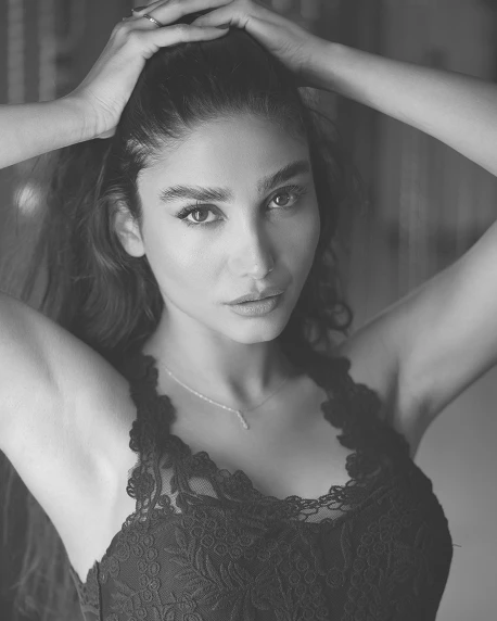a black and white photo of a woman with her hands on her head, a black and white photo, by Niyazi Selimoglu, trending on pexels, hurufiyya, posing in bra, looks like a mix of grimes, lovingly looking at camera, arabian beauty