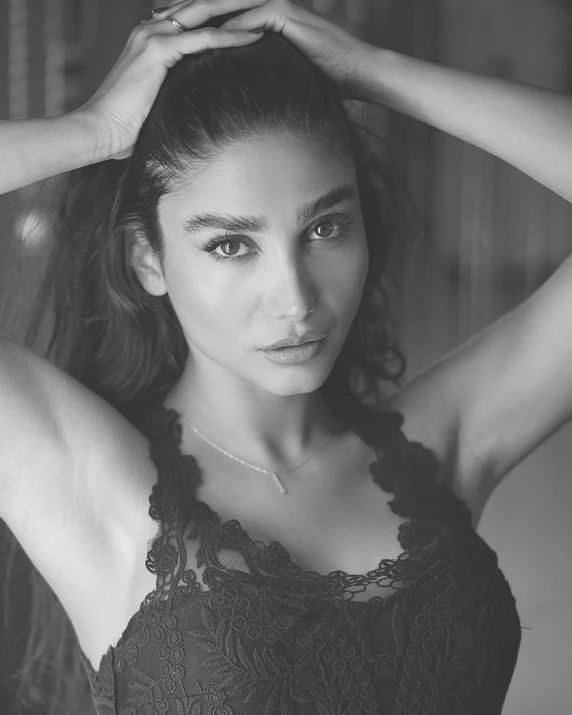 a black and white photo of a woman with her hands on her head, a black and white photo, by Niyazi Selimoglu, trending on pexels, hurufiyya, posing in bra, looks like a mix of grimes, lovingly looking at camera, arabian beauty