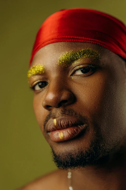 a close up of a person with a red headband, inspired by Ras Akyem, gold dust, king in yellow, queer, photo from a promo shoot