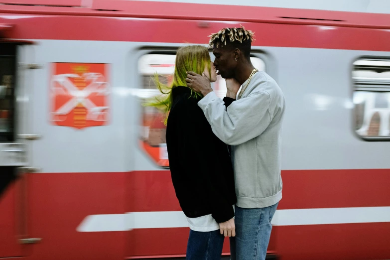 a man and a woman standing in front of a train, by Julia Pishtar, pexels contest winner, lesbian kiss, virgil abloh, xxxtentacion, a blond