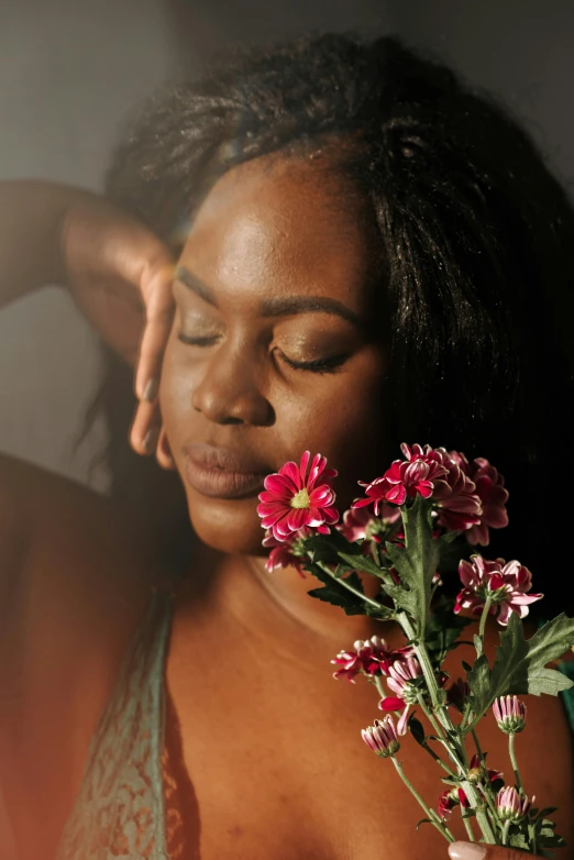 a woman holding a bouquet of flowers in front of her face, an album cover, by Dulah Marie Evans, trending on unsplash, romanticism, dark brown skin, beautiful soft light, alluring plus sized model, shot at dark with studio lights