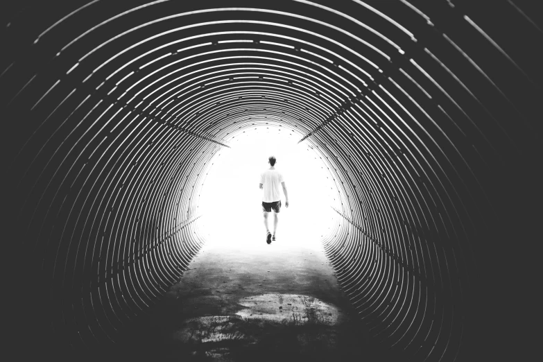 a black and white photo of a person walking through a tunnel, pexels contest winner, running, instagram post, scientist, sports photo
