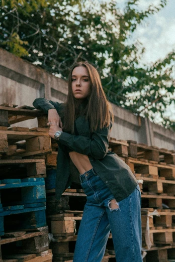 a woman leaning against a stack of wooden pallets, inspired by Elsa Bleda, pexels contest winner, wearing a bomber jacket, long hair girl, teenage, denim