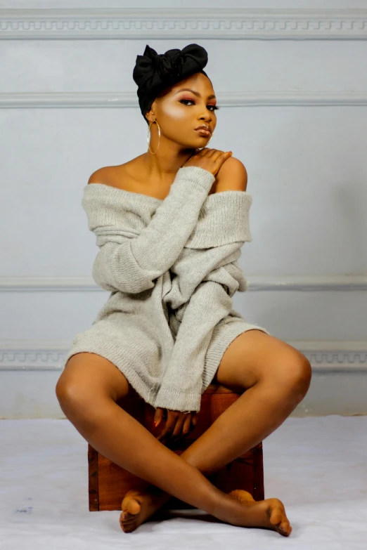 a woman sitting on top of a wooden box, by Chinwe Chukwuogo-Roy, trending on pexels, wearing an oversized sweater, seductive confident pose, wearing a simple robe, sittin